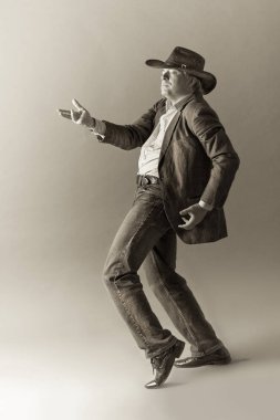 Saygın bir gri saçlı Latin erkek şapka içinde. Bir erkek bir şapka ve bir ceket sinema salonlarında gesticulating saygın gri saçlı Latin ve passionatelywith kahverengi bir arka plan uzanmış bir kol.