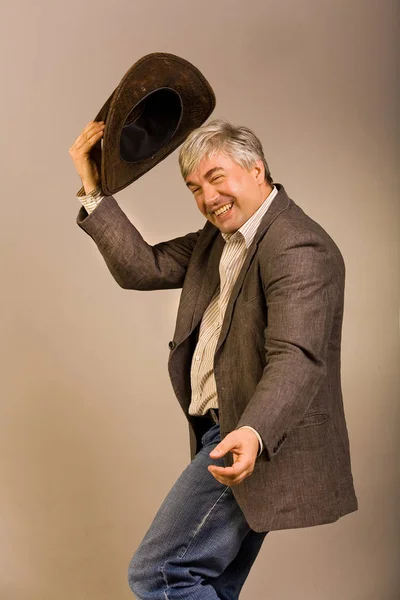 A respectable grey-haired Latino male in a hat. A respectable grey-haired Latino male in a hat and a jacket is gesticulating in the theatrical manner and dancing.