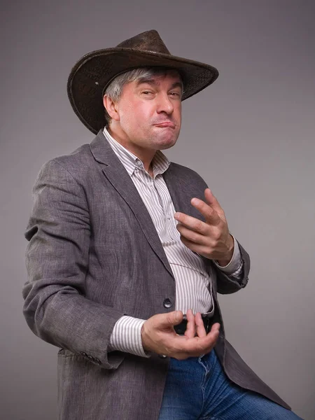 A respectable grey-haired Latino male in a hat. A respectable grey-haired Latino male in a hat and a jacket theatrically gesticulating and making a funny face.