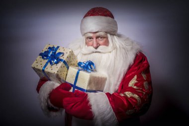 Komik ve komik Noel Baba gri bir arka plan üzerinde kutladı ve bir sürü hediyeler verir