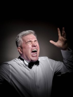 Beyaz gömlek ve siyah papyon gri saçlı, saygın bir adam duygusal bir işadamı, bir COMPER ve bir aktör görüntüdeki siyah bir arka plan karşı poz.