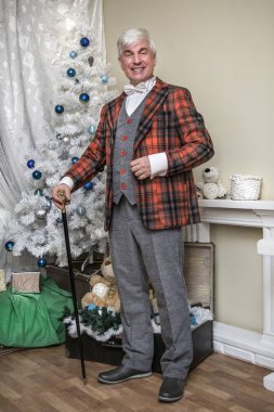 Damalı İngilizce takım elbiseli bir Noel ağacı arka planı gri saçlı bir onurlu adam.