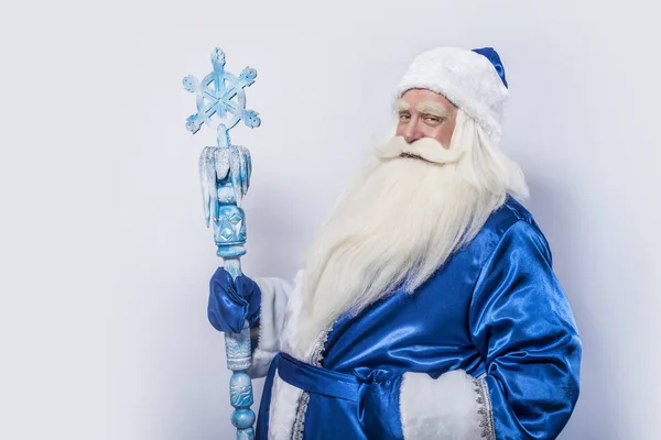 Santa Claus and Father Frost in a blue coat, a hat and with a staff is standing against a white background.