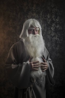 Gri saçlı sakallı ve gri bir pelerin kasvetli sihirbazında büyü karanlık bir dokulu altın arka plan uygulamak.