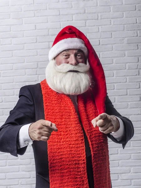 Ein grauhaariger bärtiger Mann im schwarzen Anzug und im Bild des Weihnachtsmannes. — Stockfoto