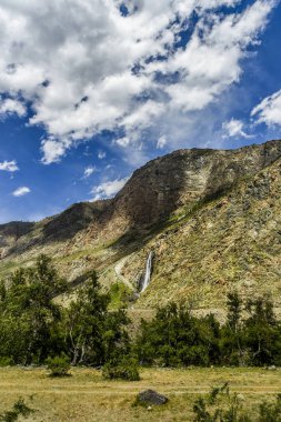 Güzel manzarası ve altay doğa manzara. Güzel ve yüksek şelale ve Altay Dağları ve kayalar gündüz mavi bulutlar gökyüzünde karşı stream.