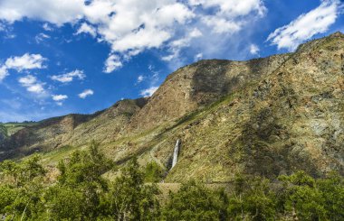 Güzel manzarası ve altay doğa manzara. Güzel ve yüksek şelale ve Altay Dağları ve kayalar gündüz mavi bulutlar gökyüzünde karşı stream.
