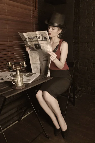 Beautiful european woman in retro style. Beautiful European woman in retro style and with a hat sitting in a cafe on a dark background.