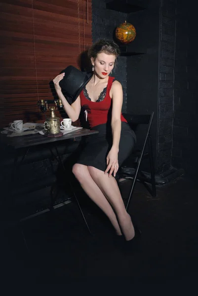 Beautiful european woman in retro style. Beautiful European woman in retro style and with a hat sitting in a cafe on a dark background.