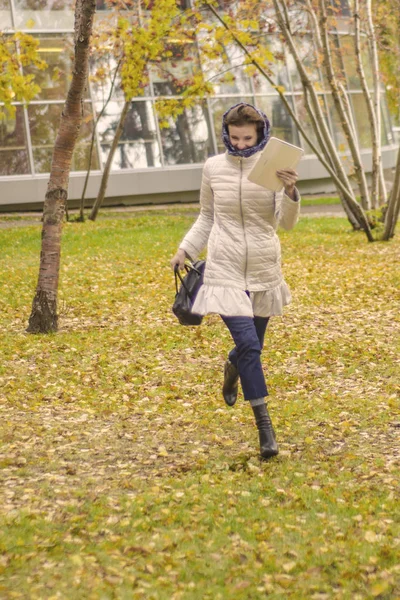 Beautiful European woman in autumn park. Beautiful european smiling woman runs through the autumn park.