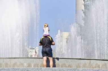 Güzel ve özgün çevre pınarlarına. Jetler bir kentsel ortamda ilginç bir ritim ile ve arka ışık ile yaz öğleden sonra insanlarla güzel bir çeşme.