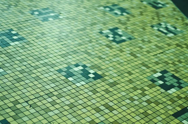 Complex, incomprehensible, original and interesting texture, pattern and background of artificial ceramic and glass mosaics and small tiles of the walls of the pool and the wall.