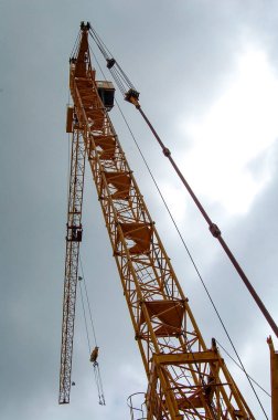 Endüstriyel ve teknolojik nesneler. Harika bir manzara ve arka planda gri fırtınalı gökyüzü bulutlu bir arka plan üzerinde bir yüksek teknoloji çalışma vinç.