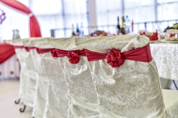 Wedding theme and style. Beautiful wedding interior and lounge with a buffet table in a light background and style, with a red decor, with a long table and chairs.