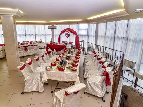 Wedding theme and style. Beautiful wedding interior and lounge with a buffet table in a light background and style, with a red decor, with a long table and chairs.