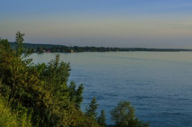 Güzel ve ilginç manzara ve yaz nehir veya göl ile yeşil çalılar ve mavi gökyüzü ile çim.