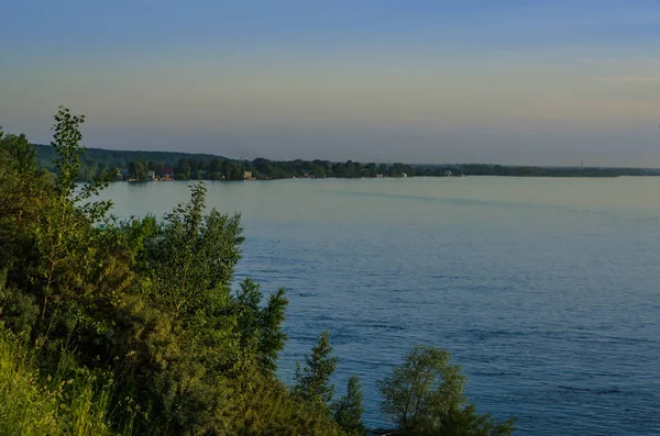 Güzel ve ilginç manzara ve yaz nehir veya göl ile yeşil çalılar ve mavi gökyüzü ile çim.