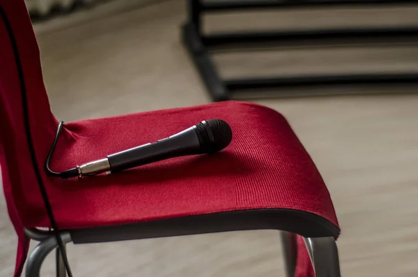 Microphone on the chair. A microphone for singing, lying on a red chair in the interior.