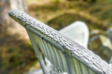 Beyaz hasır sandalye. Yaklaşık ve ağaç gövdeleri ve çalılar sandalye şezlong niteliğine beyaz hasır.