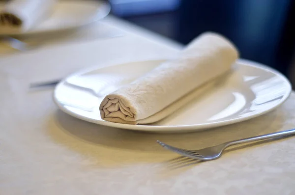 Beautiful dishes in the interior. Beautiful table setting with a knife, a spoon and a plate in the interior of a cafe and restaurant.