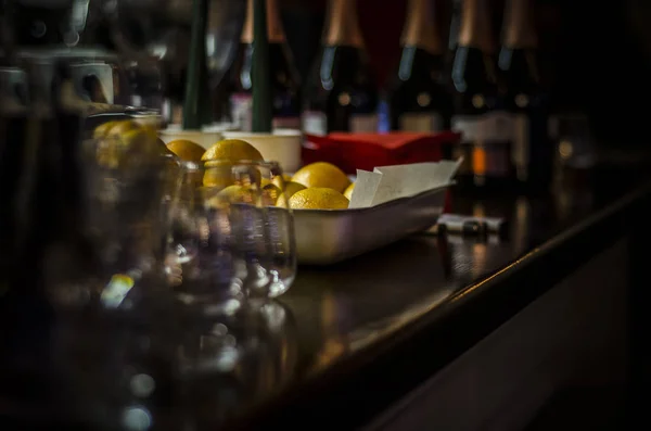 Beautiful dishes in the interior. Beautiful table setting with glasses, glasses and a plate with lemons in the dark interior of a cafe and restaurant.