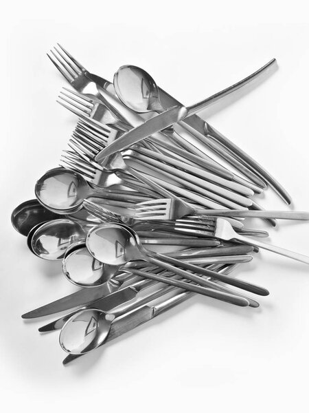 Abstraction from spoons, forks, knives. Beautiful table setting with restaurant utensils in various combinations in an interesting, creative design on a white and light background and in the form.