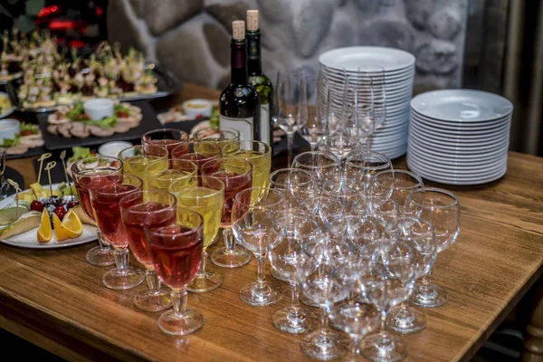 Bir güzel tablo ayarı ile çeşitli bir ve büyük snack, sandviç ve kanepeler bir tepsi ve bir kafe, bar ve Restoran İç karanlık bir arka plan üzerinde gözlüklü.