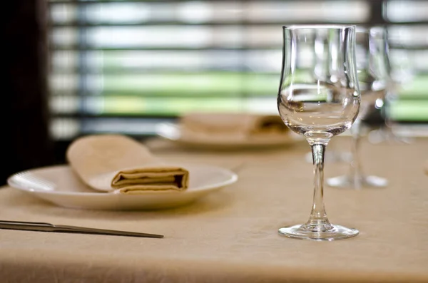 Beautiful dishes in the interior. Beautiful table setting with an empty glass with cutlery and napkins on a light background of a cafe, bar and restaurant.