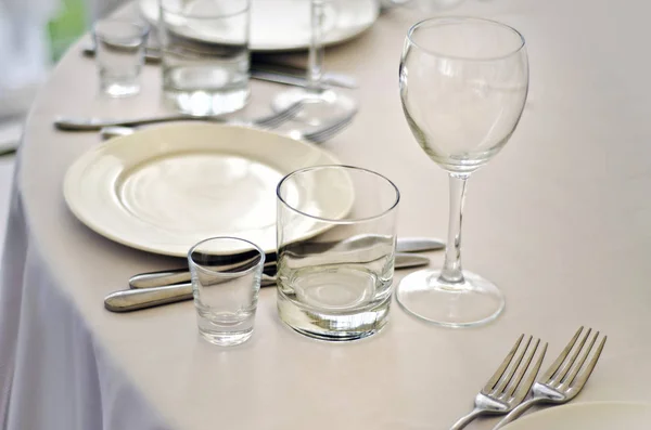 Beautiful dishes in the interior. Beautiful table setting with glasses, plates and napkins on a light background and in the interior of the cafe, bar and restaurant.