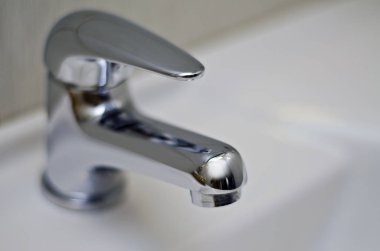 Güzel ve farklı bir konu. Güzel ve pahalı bağlantı parçaları ve parlak metal sıhhi tesisat musluk, mikser ve arka plan beyaz bir lavabo üzerinde unsurları.