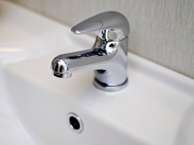 Güzel ve farklı bir konu. Güzel ve pahalı bağlantı parçaları ve parlak metal sıhhi tesisat musluk, mikser ve arka plan beyaz bir lavabo üzerinde unsurları.