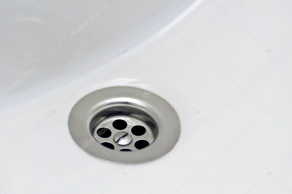 Beautiful and diverse subject. Beautiful and expensive fittings and elements of shiny metallic plumbing holes and drains on the background of a white sink