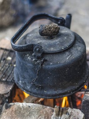 Güzel ve farklı bir konu. Bir yaz öğleden sonra doğada yangında ateşe kurum içinde eski ve harap siyah çaydanlık.