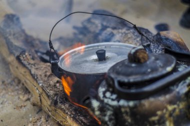 Güzel ve farklı bir konu. Bir yaz öğleden sonra doğada yangında ateşe kurum içinde eski ve harap siyah çaydanlık.