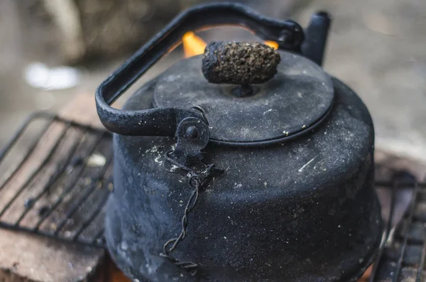 Beautiful and diverse subject. An old and dilapidated black kettle in the soot of a fire on the fire in nature in the summer afternoon.