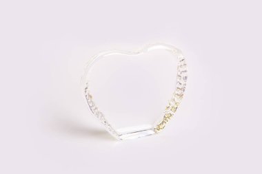 Güzel ve özgün bir görünüm ve bir ilginç, yaratıcı ve tasarımcı cam ve şeffaf hediye ve öğe, kolye, arka plan gri bir arka plan üzerinde form ve kalp şeklinde ayaklı.