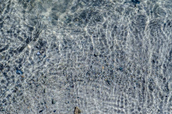 Beautiful texture of nature. Beautiful background and view of the texture of the sea, river and lake smooth surface of transparent water with a bottom of sand and stones during the day.