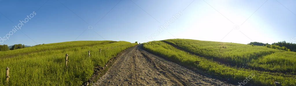 Beautiful and original panorama. Beautiful and majestic landscape and panorama of mountain and wild roads, trails during the day in summer against the background of grass and a blue clean sky.