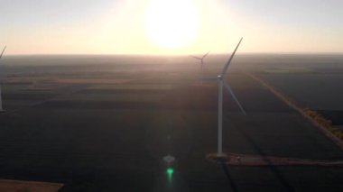 Beyaz rüzgar enerji güç kuleleri bir grup gün batımı, gün doğumukarşı alanında değirmenler. Yeşil, temiz, yenilenebilir enerji. Havadan çekilen görüntüler.