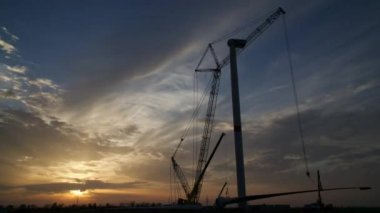 Yapım aşamasında rüzgar enerjisi güç kulesi değirmeni yapım süreci. Montaj kulesi, sütun, sütun. Yeşil, temiz, yenilenebilir enerji. Gün batımı, gün doğumu zamanı atlamalı