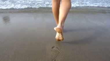 Kız çıplak ayakla sahilde kum deniz kenarında yürüyüş. Ağır çekim 250fps 