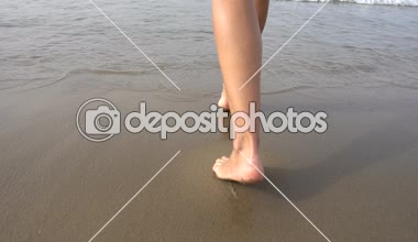Güzel bacakları suda kumsalda yürüyen güzel bir kız. Ağır çekim 250fps 
