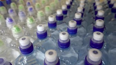 Plastik şişe maden suyu ile. Tatlı su şişeleri RAW ve satırlarındaki. Plastik şişeler, renkli kapaklar. Plastik şişe su, kapakları ile.