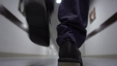 Bir adam uzun beyaz koridorda yürüyor. Bulanık arka plan. Video titreme ve gürültü içerir