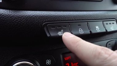 El, arabada gösterge panelindeki Isıtmalı Koltuk Yüksek düğmesine basar