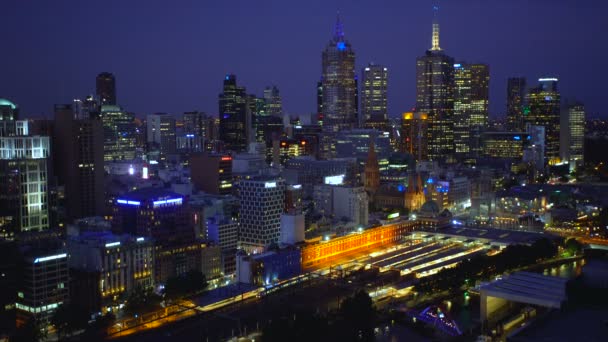 照らされたオフィスビルやフリンダース ストリート駅鉄道プラットフォーム ビクトリア オーストラリアの夕暮れ時にメルボルン オーストラリア 2018 ライトのメルボルンのスカイライン — ストック動画