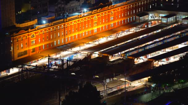旅客列車到着し夜ライトアップされたプラットフォームにフリンダース ストリート駅を出発し ビル内の照明メルボルン オーストラリア — ストック動画