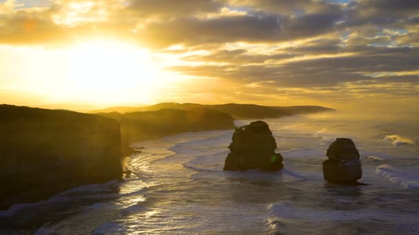 夜明けに 使徒海洋国立公園の風光明媚な海岸線ビクトリア オーストラリアの石灰岩崖の上雲の切れ間から太陽の光 — ストック動画