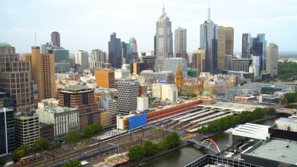 メルボルン市街のスカイライン ビクトリア オーストラリアの商業高層ビルとヤラ川のフリンダース ストリート駅でメルボルン オーストラリア 2018 通勤電車 — ストック動画