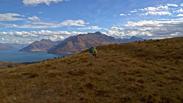 リマーカブルズ オタゴ ニュージーランドを維持するハイキング リュックサックとフィットの成熟した白人カップルの空中ドローン — ストック動画